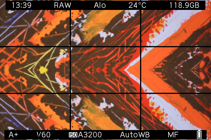On-device EOS M LiveView screenshot showing orange, yellow and black artwork mirrored around the center